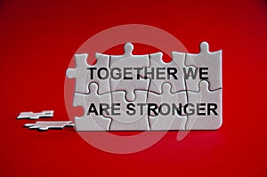 Together we are stronger text on jigsaw puzzle with red background.