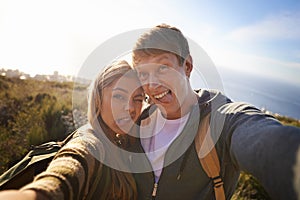 Together in their weirdness. Portrait of a happy young couple making faces for the camera while out on a hike.