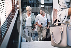 Together well get to the top. a businesswoman and businessman having a discussion while walking up the stairs in a