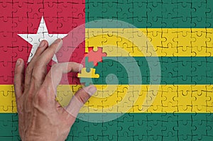 Togo flag is depicted on a puzzle, which the man`s hand completes to fold