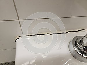 toilet in bathroom with crack in the wall or caulk