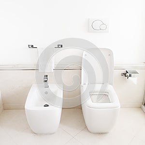 Toilet and bidet in a modern bathroom - raised lid.
