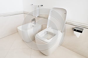 Toilet and bidet in a modern bathroom - raised lid.