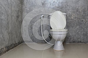 Toilet bowl with bidet shower in toilet.