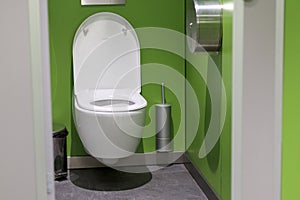 .toilet bowl and toilet paper with green tile wall