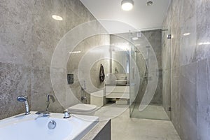 Toilet and detail of a corner shower cabin with wall mount shower attachment