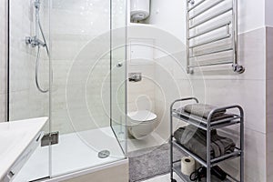 Toilet and detail of a corner shower cabin with wall mount shower attachment