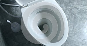 Toilet flush in bathroom. White ceramic clean toilet flushes water, toilet lid close slowly and carefully. Grey bathroom