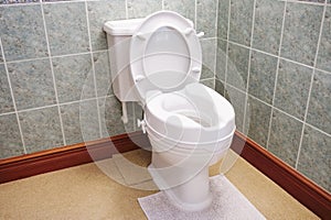 Toilet with height extension for disabled senior person indoors in house