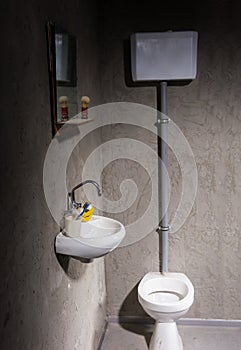 Toilet near washbasin under the mirror with shave brush on the s