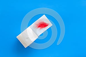 Toilet paper roll and feather for proctology diseases concept on blue background top view