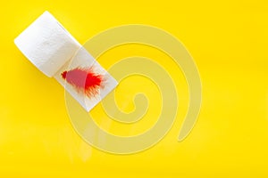 Toilet paper roll and feather for proctology diseases concept on yellow background top view mock up