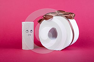 Toilet paper roll with loop as present on red background, empty roll with sad face is lookin the the roll