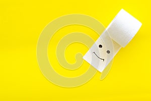Toilet paper roll with painted face for proctology diseases concept on yellow background top view mock up