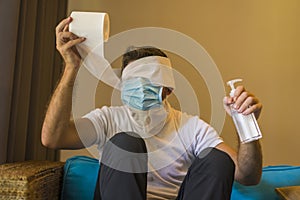 Crazy man in protective mask in home lockdown with head wrapped in tissue paper roll during coronavirus