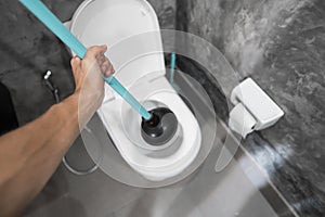 Toilet repair by hand with a Toilet Plunger. Plumbing. A plumber uses a plunger to unclog a toilet. Toilet Plunger. photo