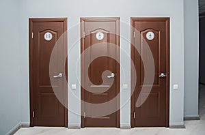 Toilet and shower room for men and women in office. Interior with three brown closed doors