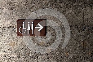 Toilet sign on concrete brick wall for man woman and disabled person, Arrow sign pointing on the way to restroom