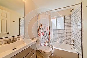 Toilet vanity and built in bathtub with floral shower curtain inside bathroom