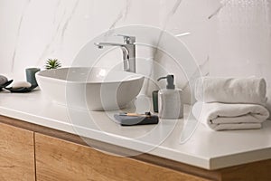 Toiletries and stylish vessel sink on countertop in modern bathroom