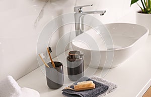 Toiletries and stylish vessel sink on light countertop in bathroom