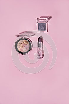 Toiletry on pink background. Lipstick, blusher, nail lacquer and eye shadow.