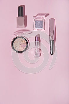Toiletry on pink background. Lipstick, blusher, nail lacquer and eye shadow. photo