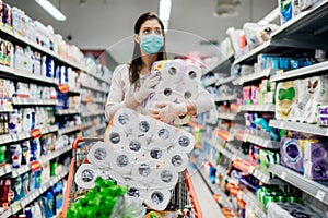 Toilette paper shortage.Woman with hygienic mask shopping for toilette paper supplies due to panic buying and product hoarding