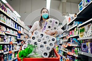 Toilette paper shortage.Woman with hygienic mask shopping for toilette paper supplies due to panic buying and product hoarding