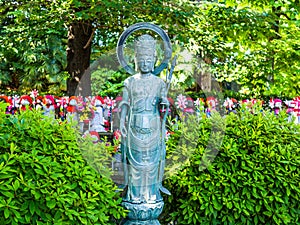TOKYO, JAPAN - APRIL 5: Close up of a stoned statue with a blurred Jizo Boddhisattvas behind at Zojo Buddhist Temple at