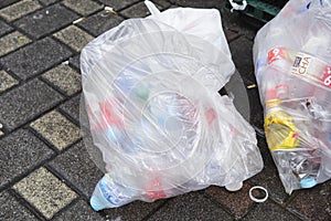 Tokyo, Japan - June 21, 2018 : Plastic bags filled with discared drink cans and plastic bottles ready for collection