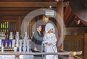 Japanese shinto wedding of a couple in kimono under a lantern of the Meiji Shrine.