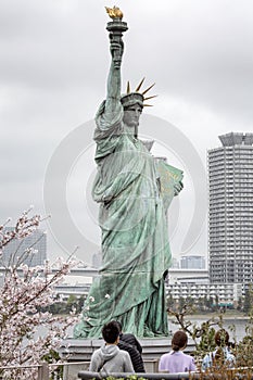 Tokyo, Japan, 04/08/2017: Statue of Liberty on Odaiba Island in blooming sakura on a gloomy day.