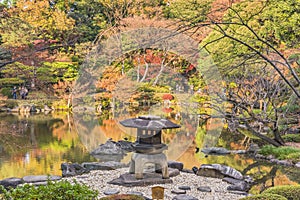 Tokyo Metropolitan Park KyuFurukawa japanese garden`s Yukimi stone lantern overlooking by red maple momiji leaves in autumn