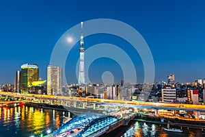 Tokyo Skytree and Sumida river at night with full moon in Asakusa district, Tokyo city, Japan