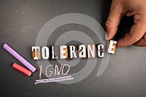 Tolerance and Ignorance concept. Text and pieces of chalk on a dark chalkboard