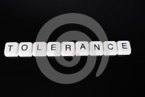 Tolerance text word title caption label cover backdrop background. Alphabet letter toy blocks on black reflective background. Whit