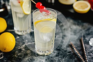 Tom Collins cocktail with lemon and cherry garnish