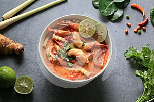 Tom Yam Kung, Spicy shrimp soup is popular Thai hot and sour soup recipe served in white bowl on cement background.