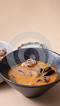 Tom yam soup with seafood and bowl with rice, veal and vegetables and angle view.