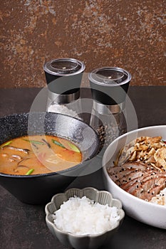 Tom yam soup with seafood and bowl with rice, veal and vegetables angle view.