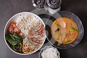 Tom yam soup with seafood and bowl with rice, veal and vegetables top view