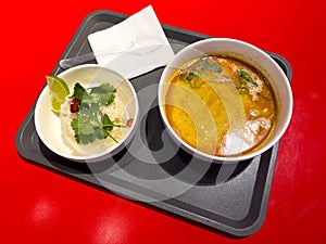 Tom yam soup on a tray on a red background