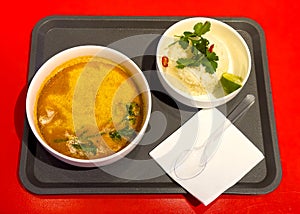 Tom yam soup on a tray on a red background