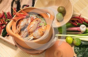 Tom Yum Goong in a clay pot spicy soup traditional thai food cuisine in Thailand on mat wicker background,Tom Yum Kung,Thai Food