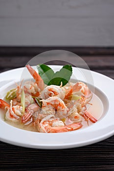 Tom Yum Goong Clear Spicy Sour Soup on wooden table top view, Thai local food