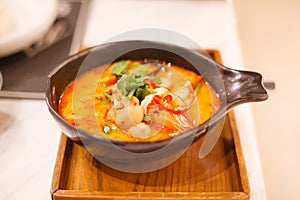 Tom Yum Goong Tom Yum Kung, Traditional Thai Sour and Spicy Tiger Prawn Soup on wooden tray, famous seafood shrimp or prawn dish
