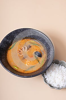 Tom yum soup with seafood and rice on beige background angle view