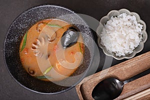 Tom yum soup with seafood and rice ondark background top view photo