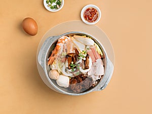 Tom Yum Xiao Wan in bowl with soup, chili sauce and spring onion top view on wooden table